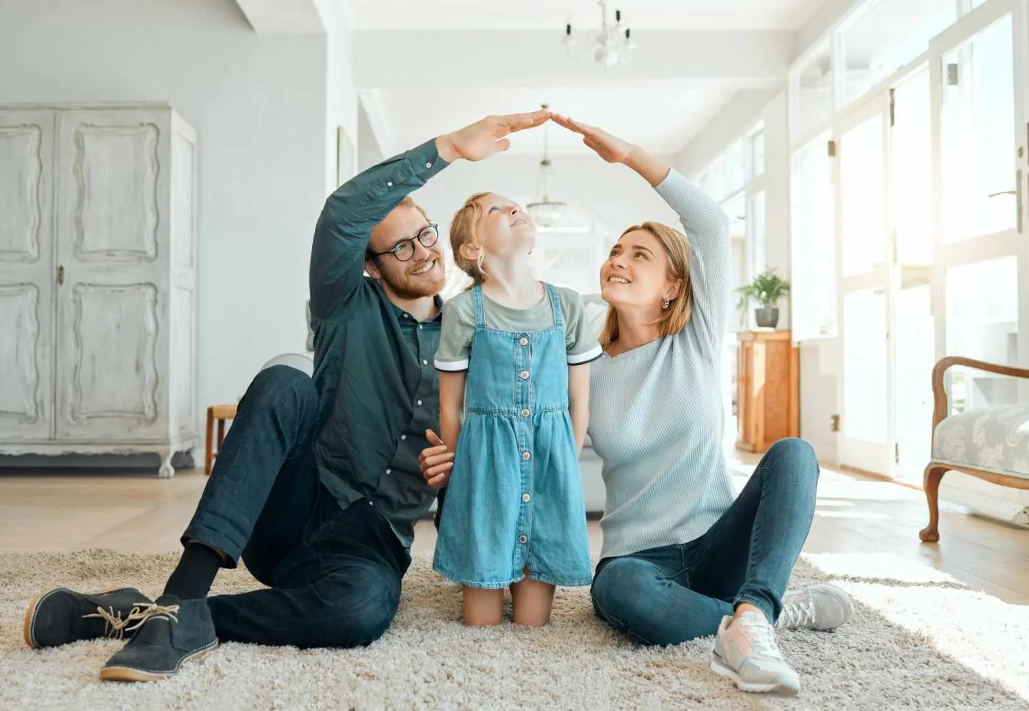 Parents and their daughter making a roof shape with their hands at home