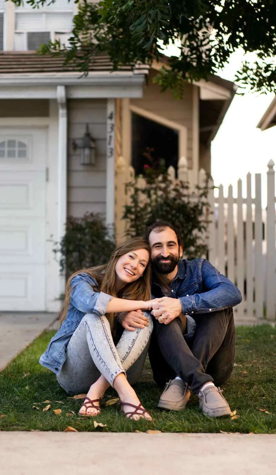 Couple sitting on the grass outside their house